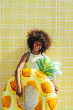 IMAGO Creative: Ende des Sommers Smiling girl with inflatable ring standing in front of yellow wall model released, Symbolfoto, OIPF02198