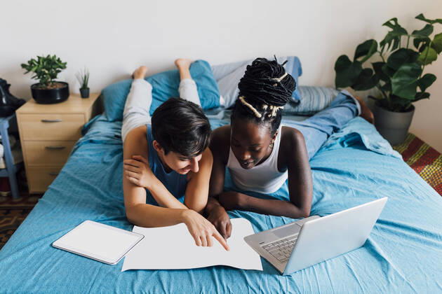 IMAGO Creative: Business, Innovative Technologie-Lösungen Lesbian couple with map planning trip lying on bed model released, Symbolfoto property released, MEUF07861