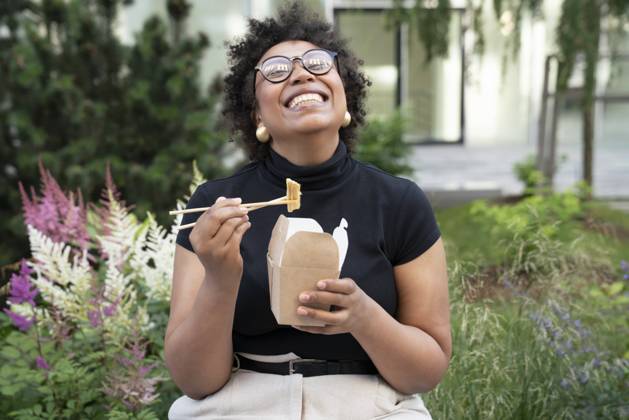 Happy young businesswoman with chopsticks and take out food sitting in office park model released, Symbolfoto, VPIF06975