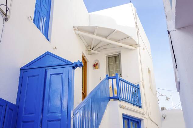 A very traditional alley view of the architecture in Chora, on the greek island Mykonos, Greece. A blue door, fence and windows of a whitewashed house against the blue sky. , 21668310.jpg, mykonos, greece, architecture, greek island, travel, greek, blue, alley, mikonos, myconos, chora, island, destination, summer, whitewashed, fence, picturesque, door, alleyway, traditional, tourist, frame, colourful, street, town, hora, stone, houses, winds, white, typical, landmark, attraction, holiday, sunny, aegean, sun, village, building, window, sightseeing, cosmopolitan, city, cyclades, tourism, mediterranean, vacation, capital, santorini, hellas,