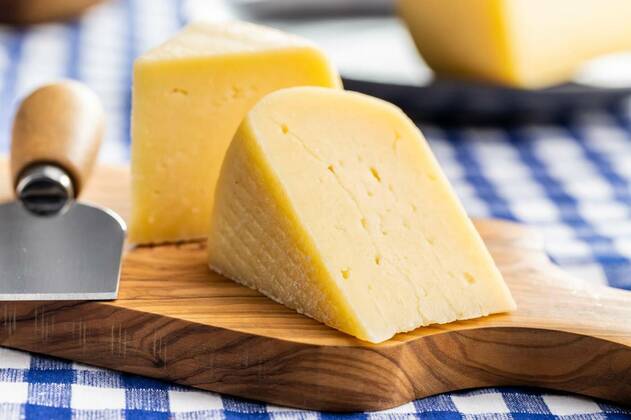  Block of hard cheese. Sliced cheese., Block of hard cheese. Sliced cheese on cutting board., Block of hard cheese. Sliced cheese on cutting board., 15.10.2021, Copyright: xjirkaejcx Panthermedia30808671.jpg