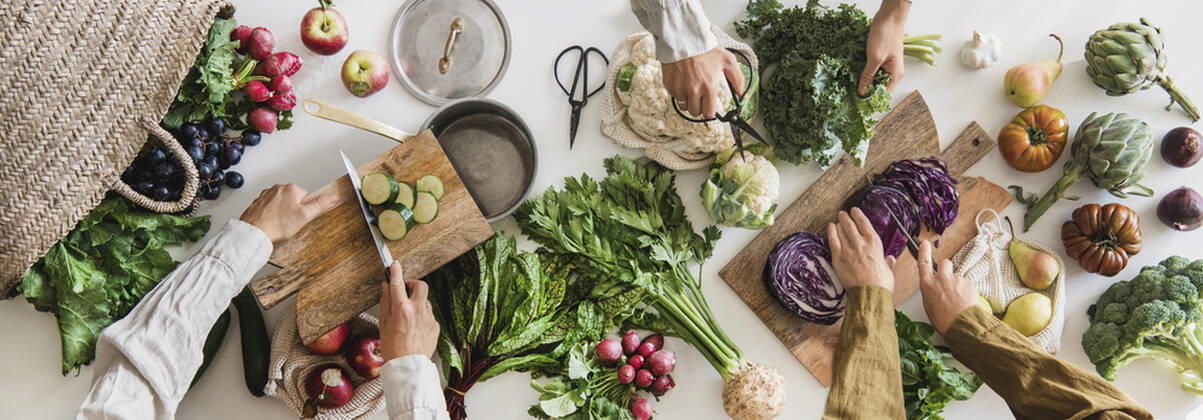 Fall vegetable vegetarian cooking background with greens and fruits Fall vegetarian cooking background. Female hands cutting greens and vegetable over table with fresh seasonal vegetables, greens, fruit from local grocery market, top view. Vegan, healthy, organic food Copyright: xAnnaxIvanovax AI191021-6