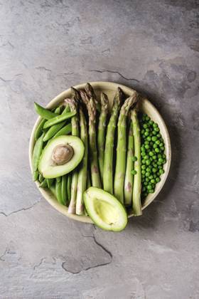 Young Green asparagus Variety of raw uncooked organic young green vegetables asparagus, peas, pod pea, avocado in ceramic plate over grey texture table background. Top view, space. Healthy eating Copyright: xNatashaxBreenx NB090418-22