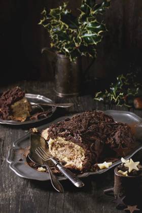 Sliced christmas chocolate yule log Sliced homemade Christmas chocolate yule log with chestnuts cream on vintage plate with forks, chocolate stars and holly branch over old wooden table. Dark rustic style. Copyright: xNatashaxBreenx NB271016-6