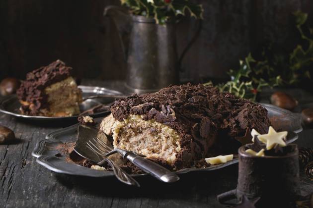 Sliced christmas chocolate yule log Sliced homemade Christmas chocolate yule log with chestnuts cream on vintage plate with forks, chocolate stars and holly branch over old wooden table. Dark rustic style. Copyright: xNatashaxBreenx NB271016-7
