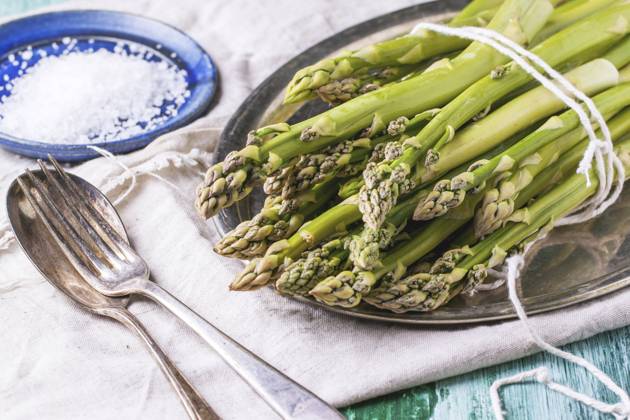 Bunch of young green asparagus on vintage tray served with ceramic plate of sea salt and silver cutlery over green wooden table. Copyright: xNatashaxBreenx xThexPicturexPantryx NB_IMG_8059
