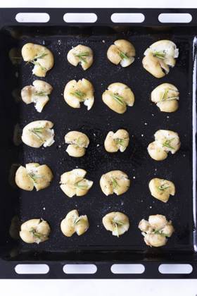 Smashed potatoes with black pepper and rosemary in a baking sheet. Copyright: xYusufxRizaxGunaydinx YG230520-16
