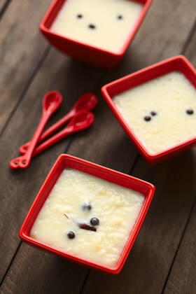 Three red bowls of the Ecuadorian dessert called morocho (coarsely ground white corn) cooked with milk, sugar and spices (cinnamon and allspice), similarly to rice pudding (Selective Focus, Focus into the middle of the lower bowl) , 14343482.jpg, morocho, cooked, sweet, dessert, pudding, food, milk, spice, condiment, cinnamon, allspice, newspice, Jamaica pepper , prepared, Ecuador, Ecuadorian, traditional, corn, maize, ground, coarse, kernel, porridge, bowl, red, vertical, white,