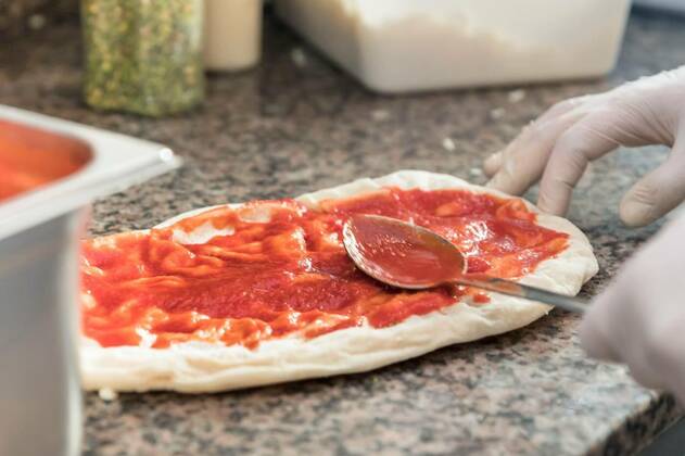  Pizza preparation, Fresh original Italian raw pizza, dough preparation in traditional style. Applying a tomato sauce., Fresh original Italian raw pizza, dough preparation in traditional style. Applying a tomato sauce., 11.05.2022, Copyright: xgermanopolix Panthermedia31402155.jpg