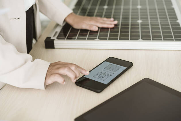 IMAGO Creative: Business, Innovative Technologie-Lösungen Close-up of woman using mobile phone with solar panel on desk model released, Symbolfoto property released, EBBF06263