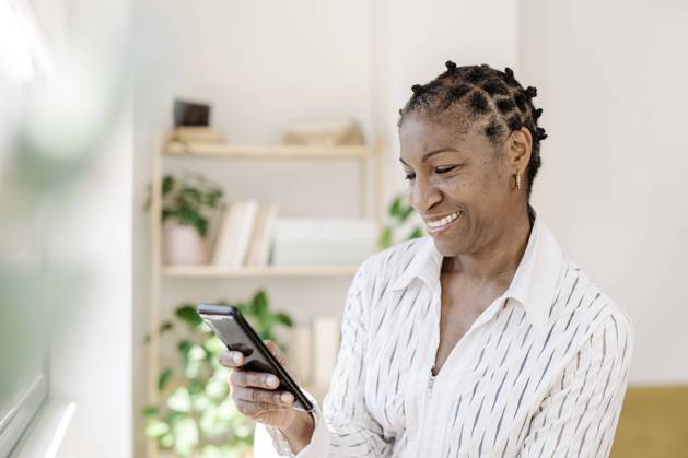 IMAGO Creative: Business, Innovative Technologie-Lösungen Smiling woman using smart phone at home model released, Symbolfoto property released, JCZF01075