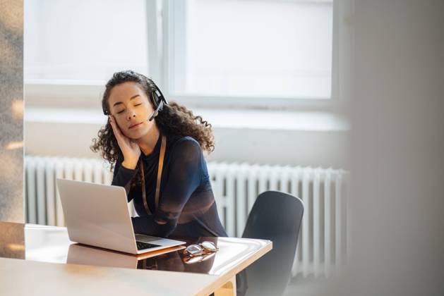 IMAGO Creative: Business, Innovative Technologie-Lösungen Young businesswoman wearing headset sitting with eyes closed at desk in office model released, Symbolfoto property released, JOSEF12858