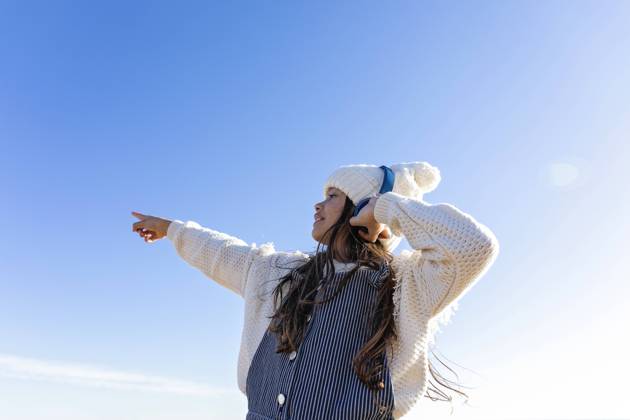 IMAGO Creative: Business, Innovative Technologie-Lösungen Girl enjoying music through headphones gesturing in front of blue sky model released, Symbolfoto, MEGF00101