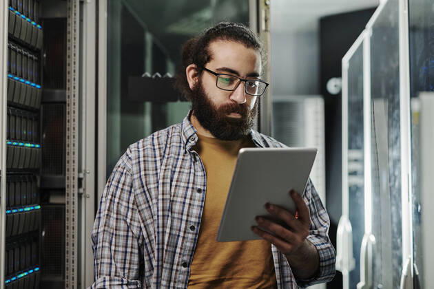 IMAGO Creative: Business, Innovative Technologie-Lösungen Technician wearing eyeglasses looking at tablet PC in server room model released, Symbolfoto property released, DSHF00578