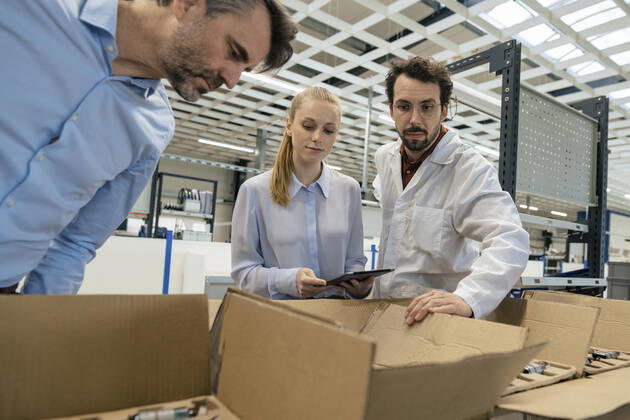 IMAGO Creative: Business, Inflation und Lieferketten Engineer standing by businessman and businesswoman examining equipment in box at factory model released, Symbolfoto property released, JOSEF13282