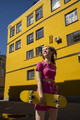 IMAGO Creative, Jahreszeit Sommer, Sommer in der Stadt Woman with skateboard standing in front of building on sunny day model released, Symbolfoto, VPIF07374