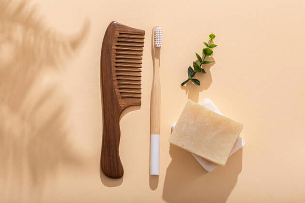 Eco friendly tools Wooden hair comb, eco bamboo toothbrush, natural soap on beige pastel background with tropical leaves shadows on sunny morning. Washing and tooth cleaning morning routine, zero waste living, top view . Copyright: xZoonar.com OlenaxYeromenkox 16619567