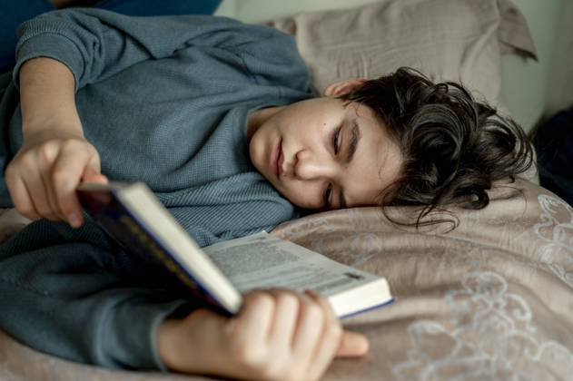 Boy reading novel lying on bed at home model released, Symbolfoto property released, ANAF00494