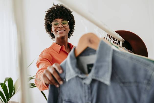 Smiling businesswoman wearing eyeglasses holding clothes at home office model released, Symbolfoto property released, EBBF06863