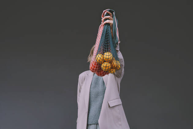 Woman covering face with mesh bag in front of gray wall model released, Symbolfoto, NDEF00065