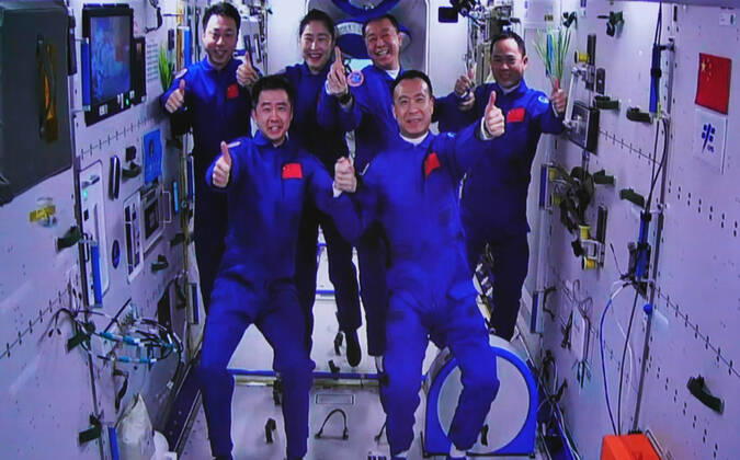 (221130) -- JIUQUAN, Nov. 30, 2022 -- This image captured at the Jiuquan Satellite Launch Center in northwest China shows the Shenzhou-15 and Shenzhou-14 crew taking a group picture with their thumbs up after a historic gathering in space on Nov. 30, 2022. The three astronauts aboard China s Shenzhou-15 spaceship entered the country s space station and met with another astronaut trio on Wednesday, a historic gathering that added the manpower at the in-orbit space lab to six for the first time. Chen Dong, the commander of the Shenzhou-14 crew, opened the hatch at 7:33 a.m. (Beijing Time). The three space station occupants greeted the new arrivals with warm hugs and then they took a group picture with their thumbs up, shouting in chorus 