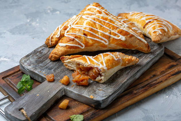 IMAGO Creative, Food, Gebäck, Apfeltaschen Puff pastry turns with apple filling. Puff pastry turnovers filled with apples on a wooden serving board, selective focus. Homemade food concept. Copyright: xZoonar.com MarinaxSaprunovax 15046852