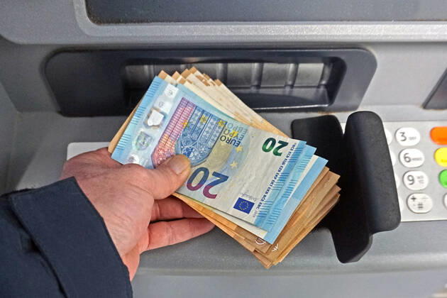 Cash supply from an ATM A person withdraws a large amount of cash from an ATM in 50 and 20 euro bills