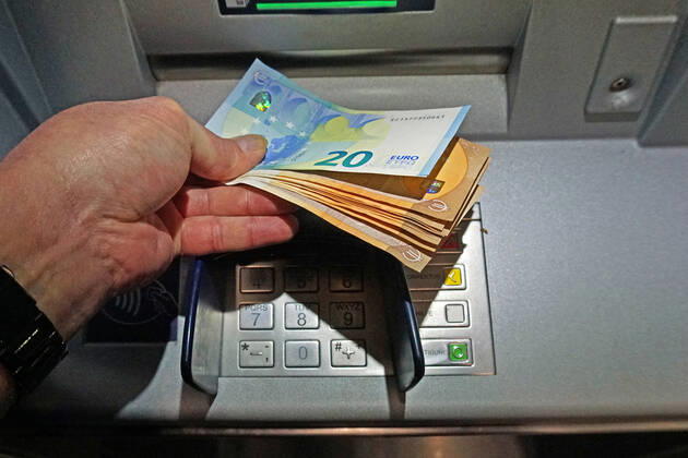 Cash supply from an ATM A person withdraws a large amount of cash from an ATM in 50 and 20 euro bills