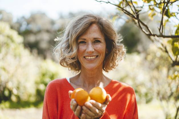 Happy blond woman with organic orange fruits model released, Symbolfoto property released, JOSEF15688