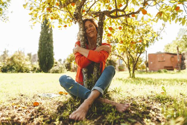 Mature woman with eyes closed hugging orange fruit tree model released, Symbolfoto property released, JOSEF15700