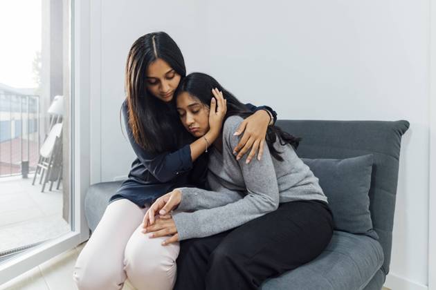 IMAGO Creative, Lifestyle, Leben in einer Wohngemeinschaft, WG Young woman consoling sister on sofa in living room model released, Symbolfoto property released, MEUF08657