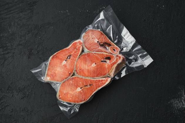  Overhead view of raw salmon steak in vacuum packaging, Overhead view of raw salmon steak in vacuum packaging on dark background, Overhead view of raw salmon steak in vacuum packaging on dark background, 07.10.2022, Copyright: xBoomeartx Panthermedia32300170.jpg
