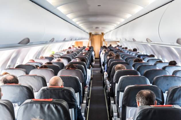 Interior of commercial airplane with passengers on their seats during flight. Interior of commercial airplane with unrecognizable passengers on their seats during flight shot from the rear of airplane. Copyright: xZoonar.com MatejxKastelicx 12437083