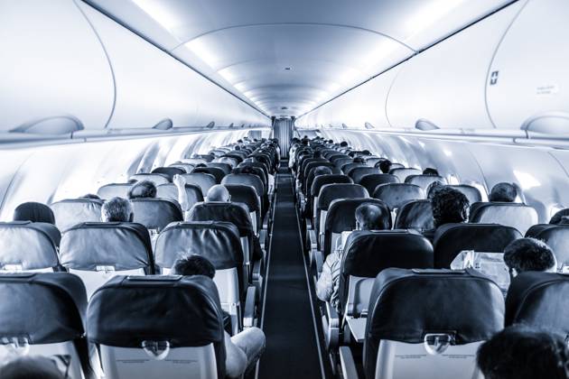 Interior of commercial airplane with passengers on their seats during flight. Interior of commercial airplane with unrecognizable passengers on their seats during flight shot from the rear of airplane. Black and white, blue toned image. Copyright: xZoonar.com MatejxKastelicx 12545661