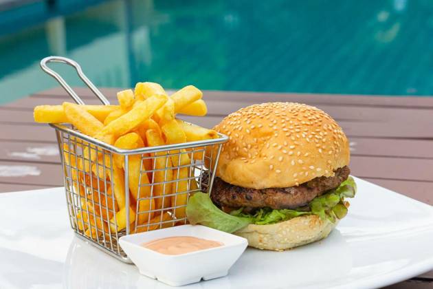 Classic burger with stainless steel basket of french fries and pink sauce dip, Classic burger with stainless steel basket of french fries and pink sauce dip plate by swimming pool. Chicken hamburger at fancy restaurant, fast food combo meal concepts, Classic burger with stainless steel basket of french fries and pink sauce dip plate by swimming pool. Chicken hamburger at fancy restaurant, fast food combo meal concepts, 01.12.2022, Copyright: xJosux Panthermedia33123580.jpg