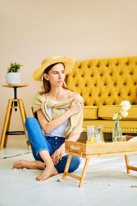 IMAGO Creative, Gesellschaft, Leisure Sickness Barefoot girl in jeans, shirt and straw hat sitting on the floor near side table, Barefoot girl in jeans, shirt and straw hat sitting on the floor near side table with fresh drink, Barefoot girl in jeans, shirt and straw hat sitting on the floor near side table with fresh drink model released, Symbolfoto , 05.12.2022, Copyright: xBoomeartx Panthermedia33137179.jpg
