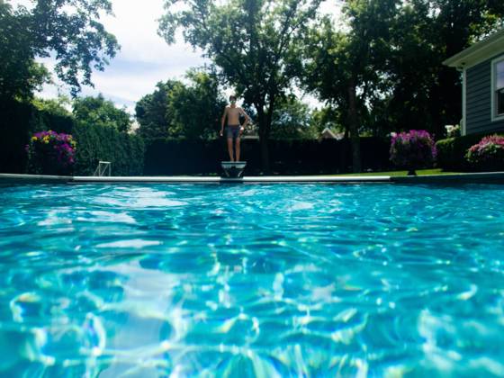 Boy jumps off diving board into backyard pool in summer sunshine Gurnee, Illinois, United States CR_WVNP230125E-1091177-01 ,model released, Symbolfoto