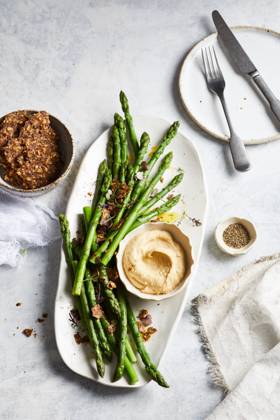 Top view of yummy hummus with asparagus served on white plate near bowl of crispy seed crackers on marble table in kitchen GeorgiaGold_ID12873_391218_001 Copyright: xGeorgiaxGoldx Model Released