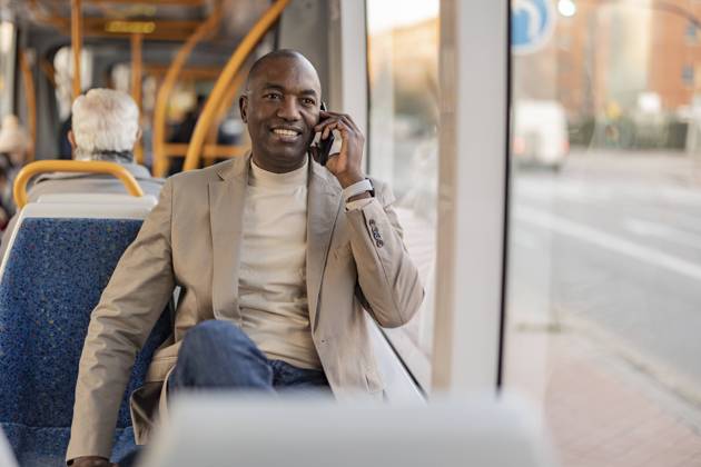 Smiling mature commuter talking on smart phone in cable car model released, Symbolfoto, JCCMF09270