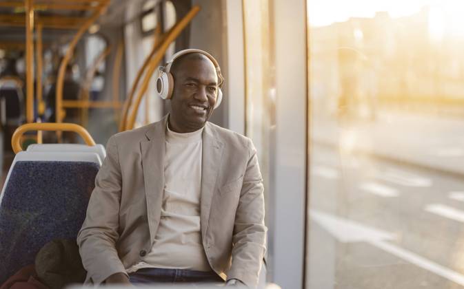 IMAGO Creative, Urban Lifestyle Smiling businessman listening to music on headphones in cable car model released, Symbolfoto, JCCMF09275