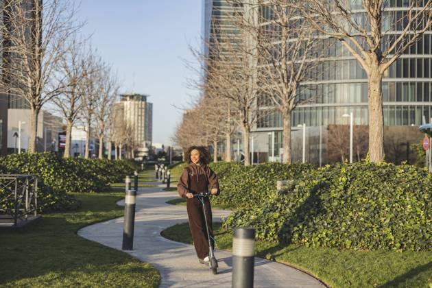 IMAGO Creative, Urban Lifestyle Young woman riding push scooter on footpath in city model released, Symbolfoto, JCCMF09405