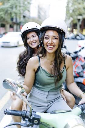 Happy woman with friend sitting on electric scooter model released, Symbolfoto, JJF00213