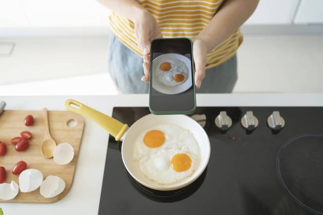 Woman photographing fried eggs with smart phone at home model released, Symbolfoto property released, SVKF01264
