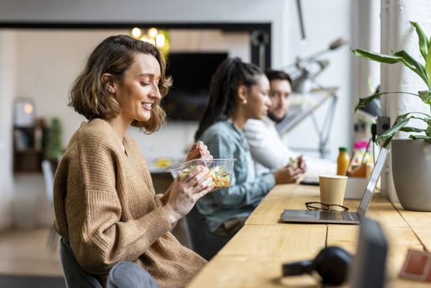 Smiling businesswoman eating salad in lunch break in office model released, Symbolfoto property released, WPEF07038