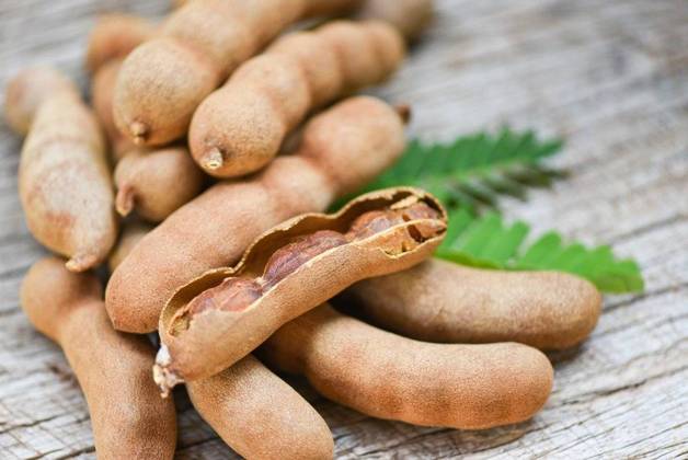 RECORD DATE NOT STATED Tamarind and leaves tropical fruit Sweet tamarind on wooden background; Tamarinde und verlässt tropisch Frucht suesse Tamarinde am hölzern Hintergrund IST_23395_10117