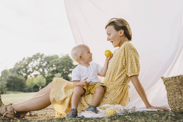Smiling boy giving fruit to mother sitting in park model released, Symbolfoto, NDEF00399