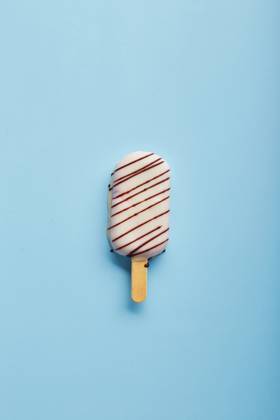 Mousse dessert with fruit flavors in the form of popsicle ice cream on blue background. Mousse dessert with fruit flavors in the form of popsicle ice cream covered with white chocolate on blue background. Copyright: xZoonar.com BurakovaxIrinax 18196196