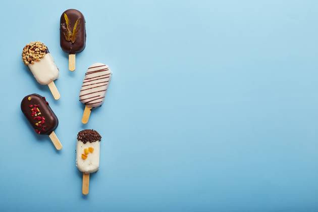 Mousse dessert with fruit flavors in the form of popsicle ice cream on blue background. Mousse dessert with fruit flavors in the form of popsicle ice cream covered with white and dark chocolate on a blue background. Copyright: xZoonar.com BurakovaxIrinax 18196417