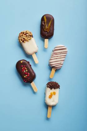 Mousse dessert with fruit flavors in the form of popsicle ice cream on blue background. Mousse dessert with fruit flavors in the form of popsicle ice cream covered with white and dark chocolate on a blue background. Copyright: xZoonar.com BurakovaxIrinax 18231111