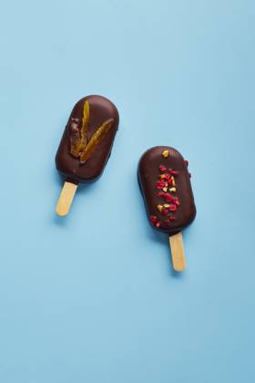 Mousse dessert with fruit flavors in the form of popsicle ice cream on blue background. Mousse dessert with fruit flavors in the form of popsicle ice cream covered with dark chocolate on blue background. Copyright: xZoonar.com BurakovaxIrinax 18231132